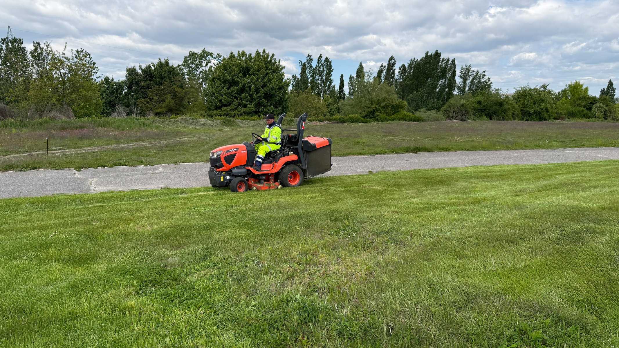Traktorek Kubota koszący trawnik przy terenach rekreacyjnych — koszenie terenów sportowych