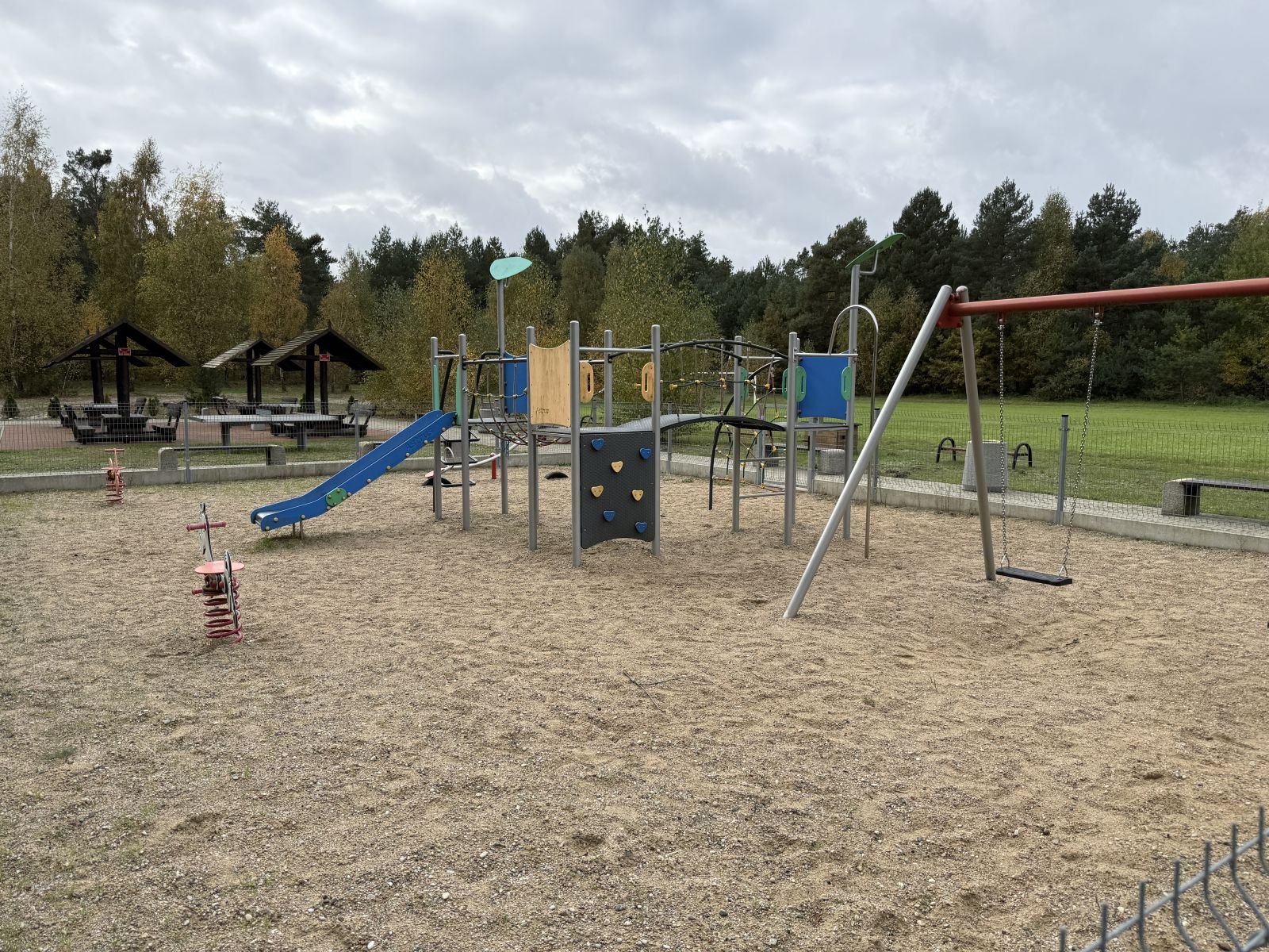Plac zabaw ze zjeżdżalnią i huśtawkami na nawierzchni piaskowej — konserwacja placów zabaw