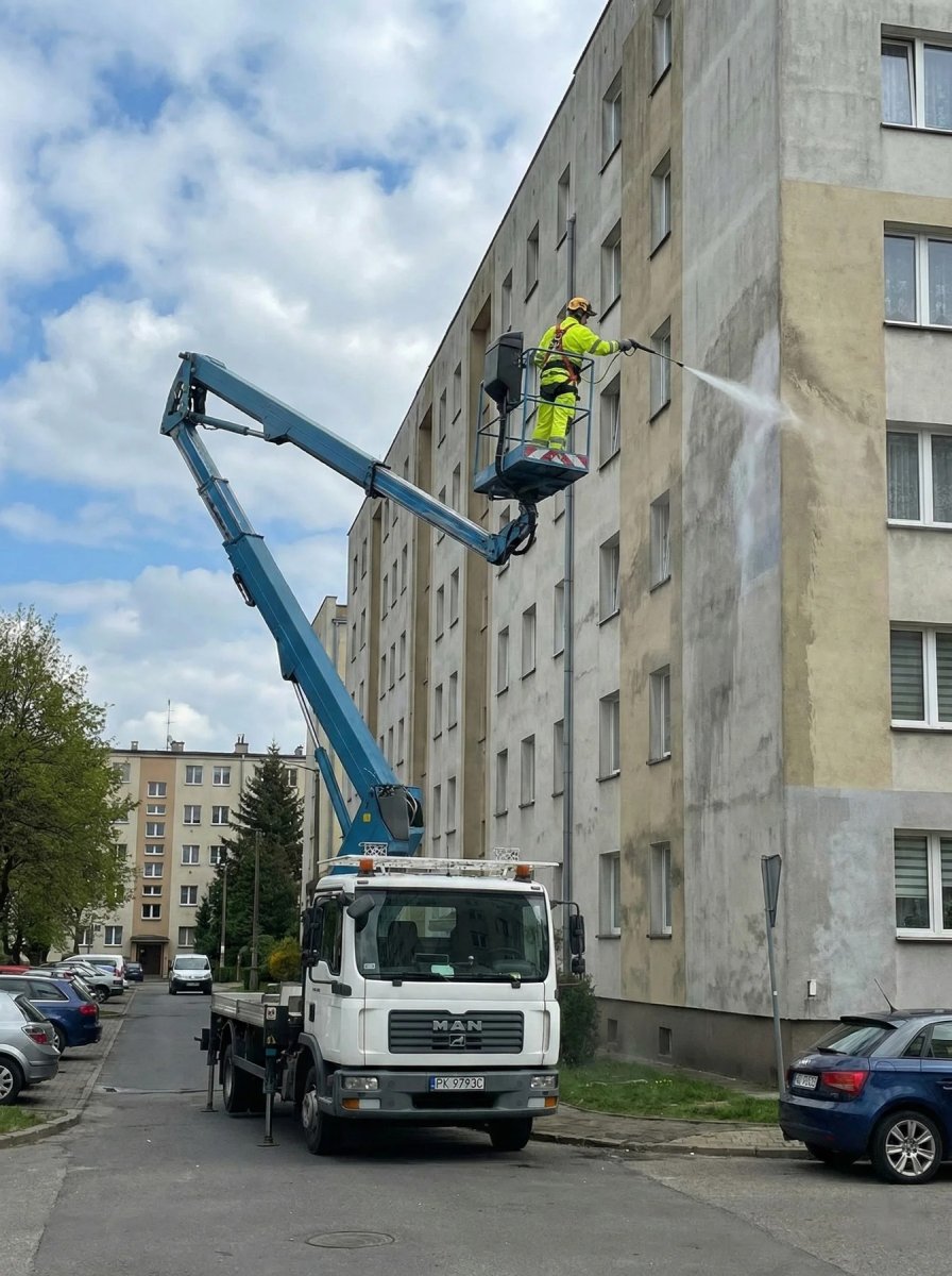 Mycie elewacji bloku mieszkalnego z podnośnika koszowego — prace na wysokości Kalisz