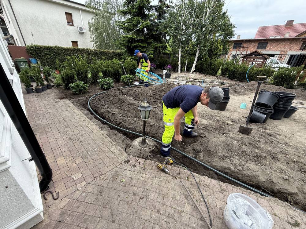 Układanie instalacji nawadniającej wokół rabat i lampy ogrodowej