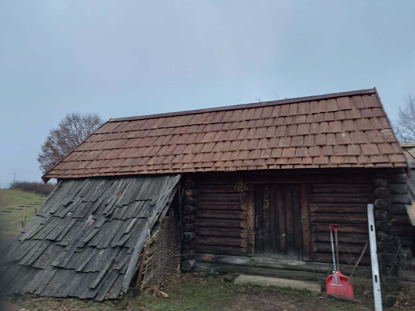 Chałupa zrębowa z nowym dachem gontowym obok starego pokrycia — efekt przed i po