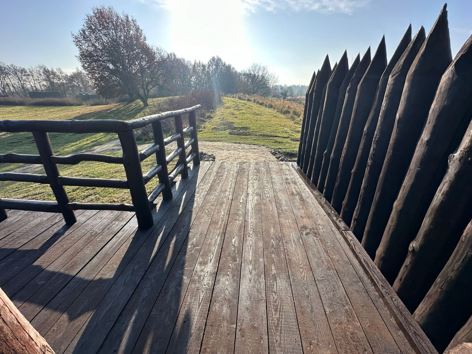 Odnowiony pomost z balustradą i palisadą przy wieży obronnej — naprawa pomostów drewnianych