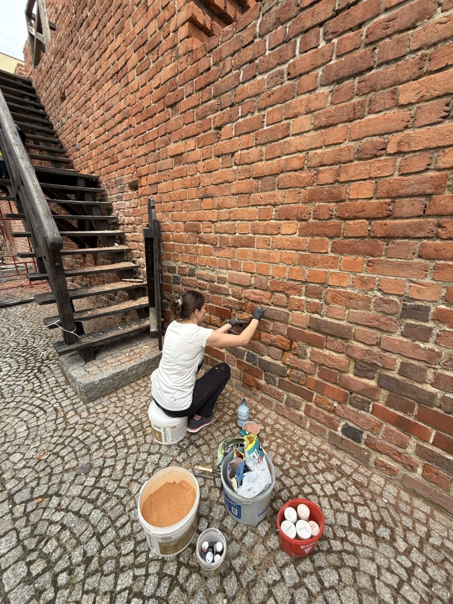 Konserwacja cokołu i lica muru przy drewnianych schodach ganku obronnego