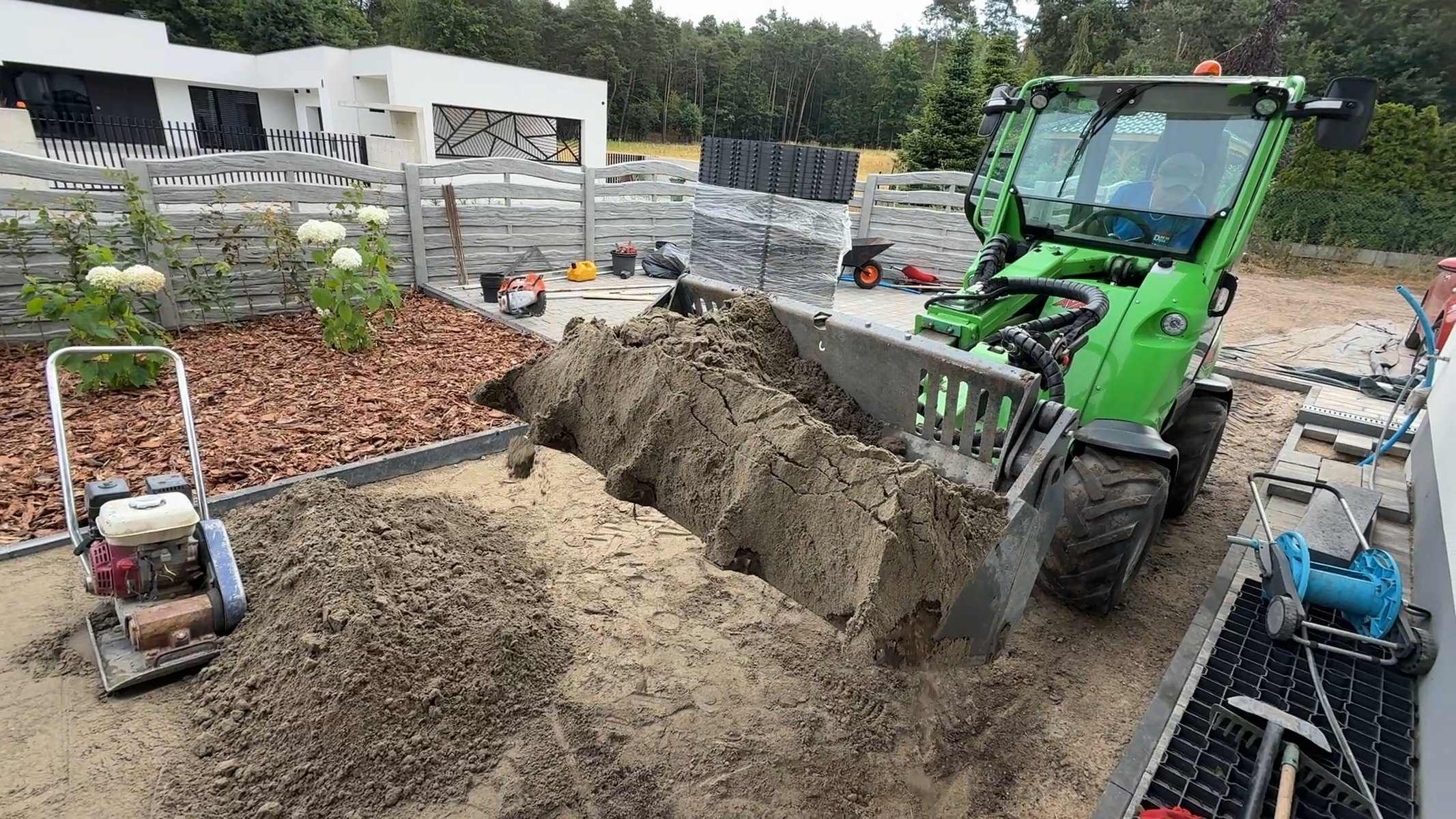 Ładowarka rozściela podsypkę pod nawierzchnię podjazdu — korytowanie i podbudowa
