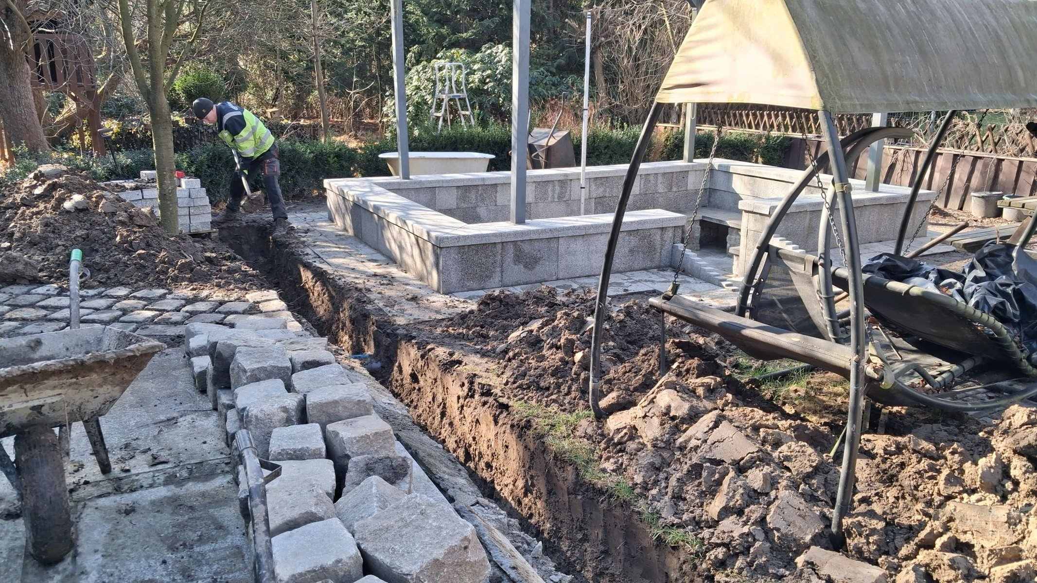 Wykop pod instalację w ogrodzie przy murkach granitowych — roboty ziemne GardenProducts