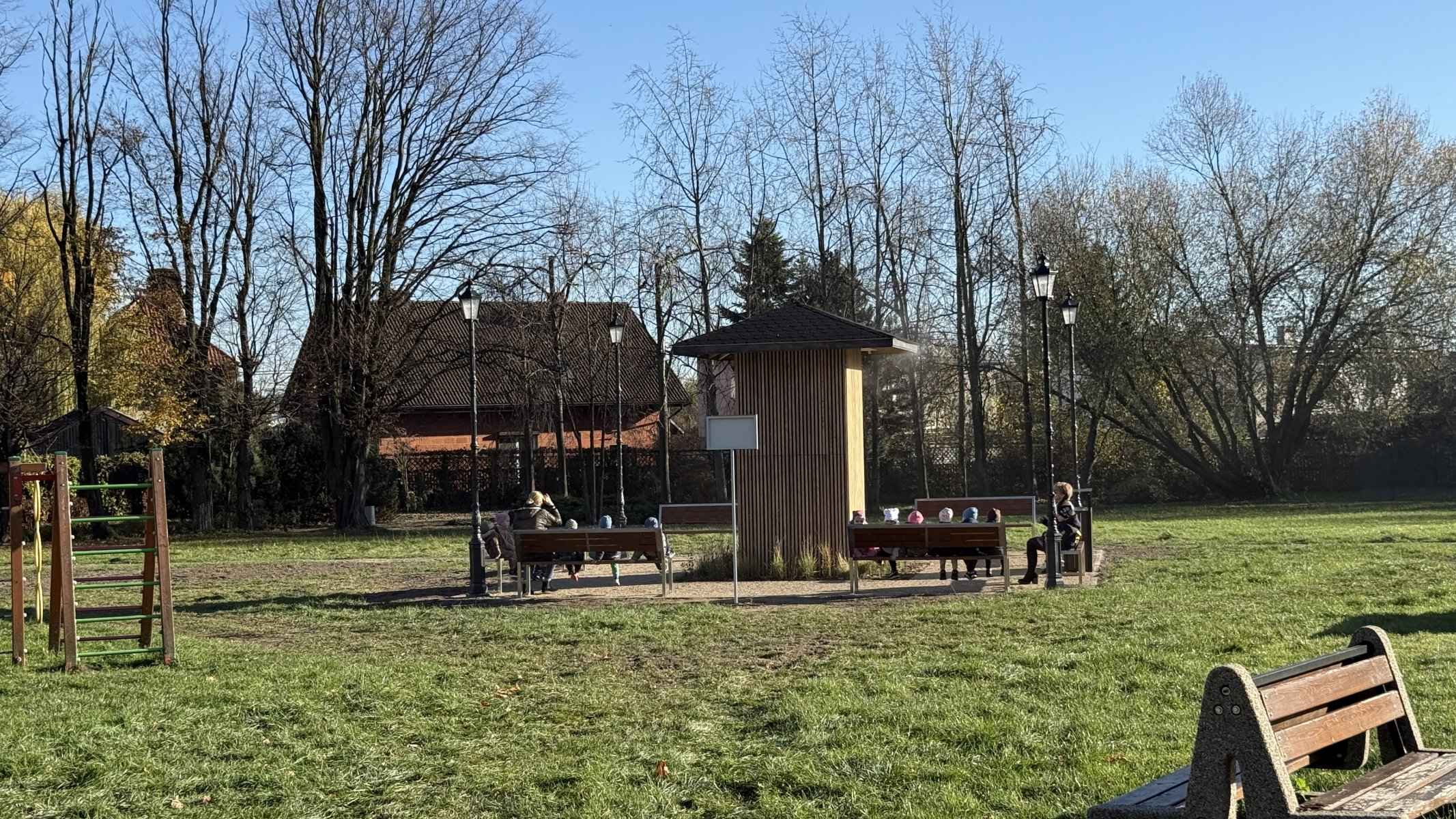Mieszkańcy odpoczywający na ławkach przy tężni sonicznej w Raszkowie