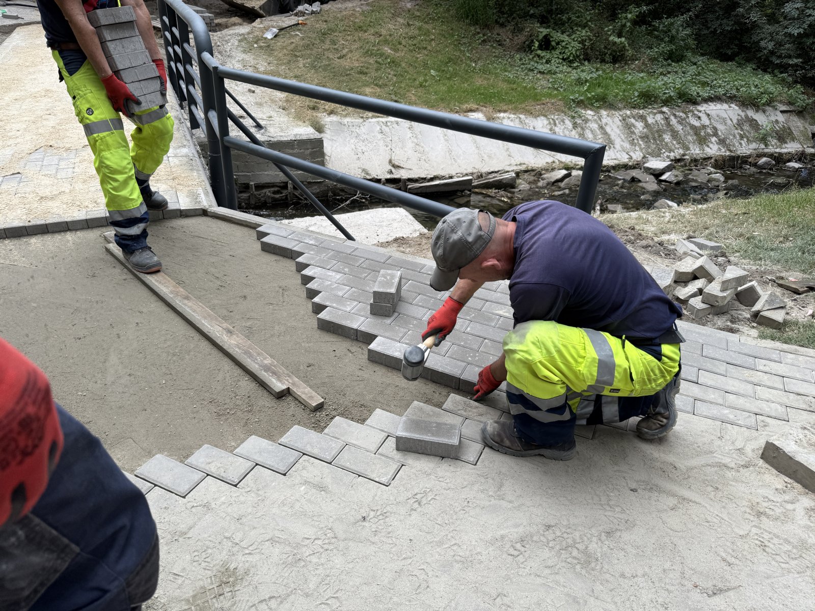 Układanie kostki betonowej na pochylni przy kładce w parku