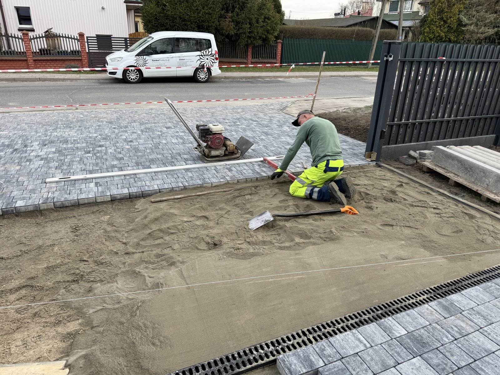 Wyrównywanie podsypki pod kostkę brukową łatą i poziomicą — brygada GardenProducts