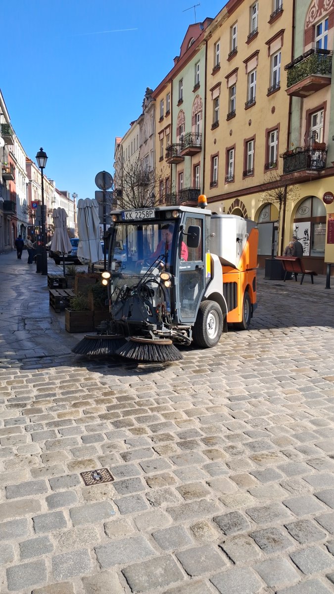 Zamiatarka mechaniczna na rynku wśród kamienic — utrzymanie czystości starego miasta