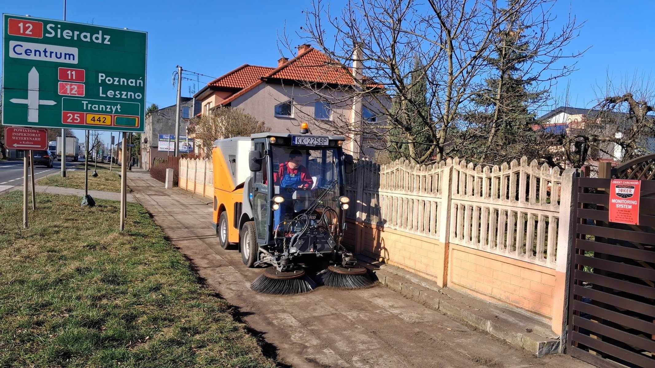 Zamiatarka czyści chodnik przy drodze krajowej — mechaniczne zamiatanie chodników