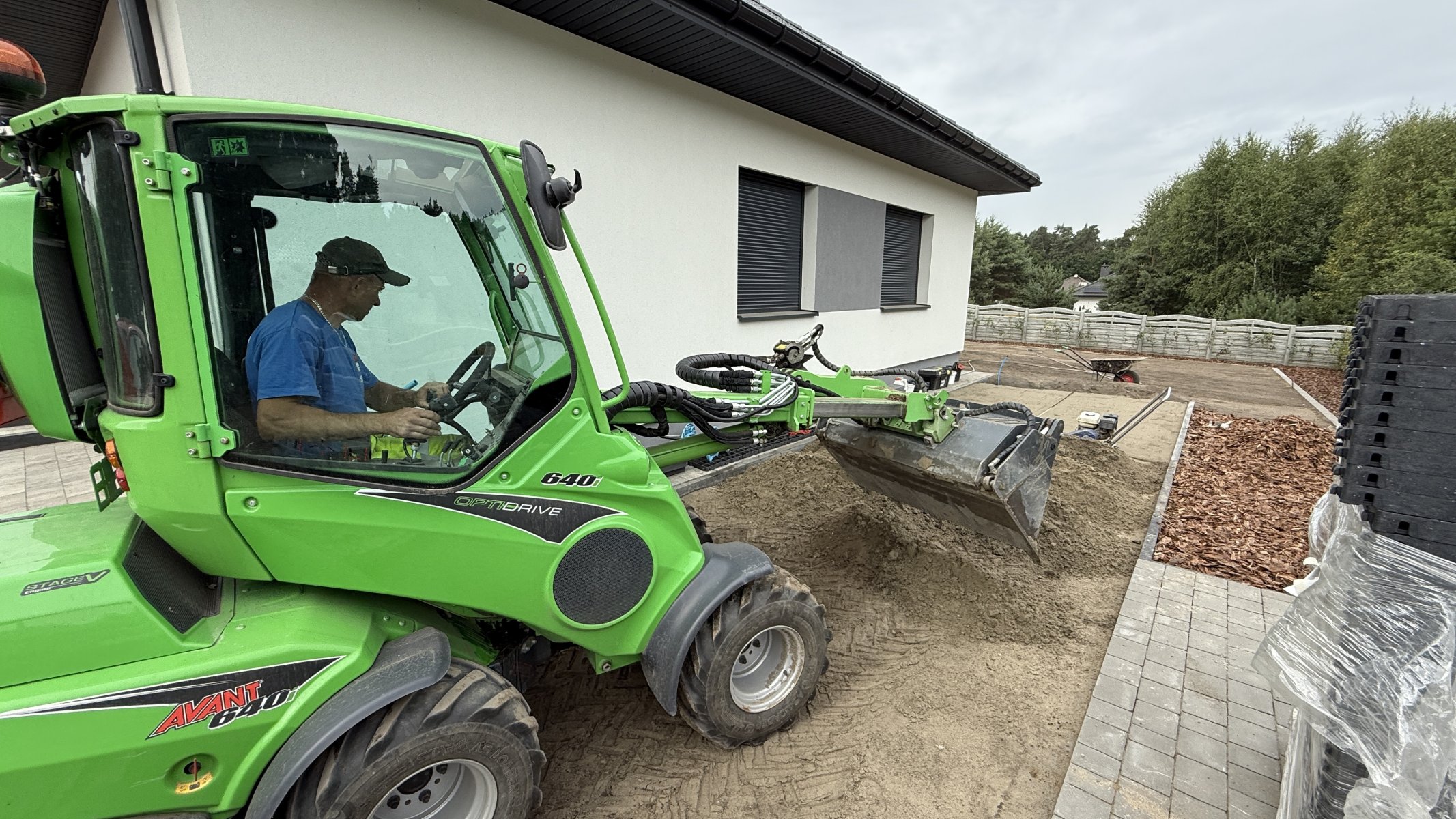 Ładowarka Avant 640 z łyżką rozgarnia piasek przy budowie ogrodu — wynajem miniładowarki Kalisz