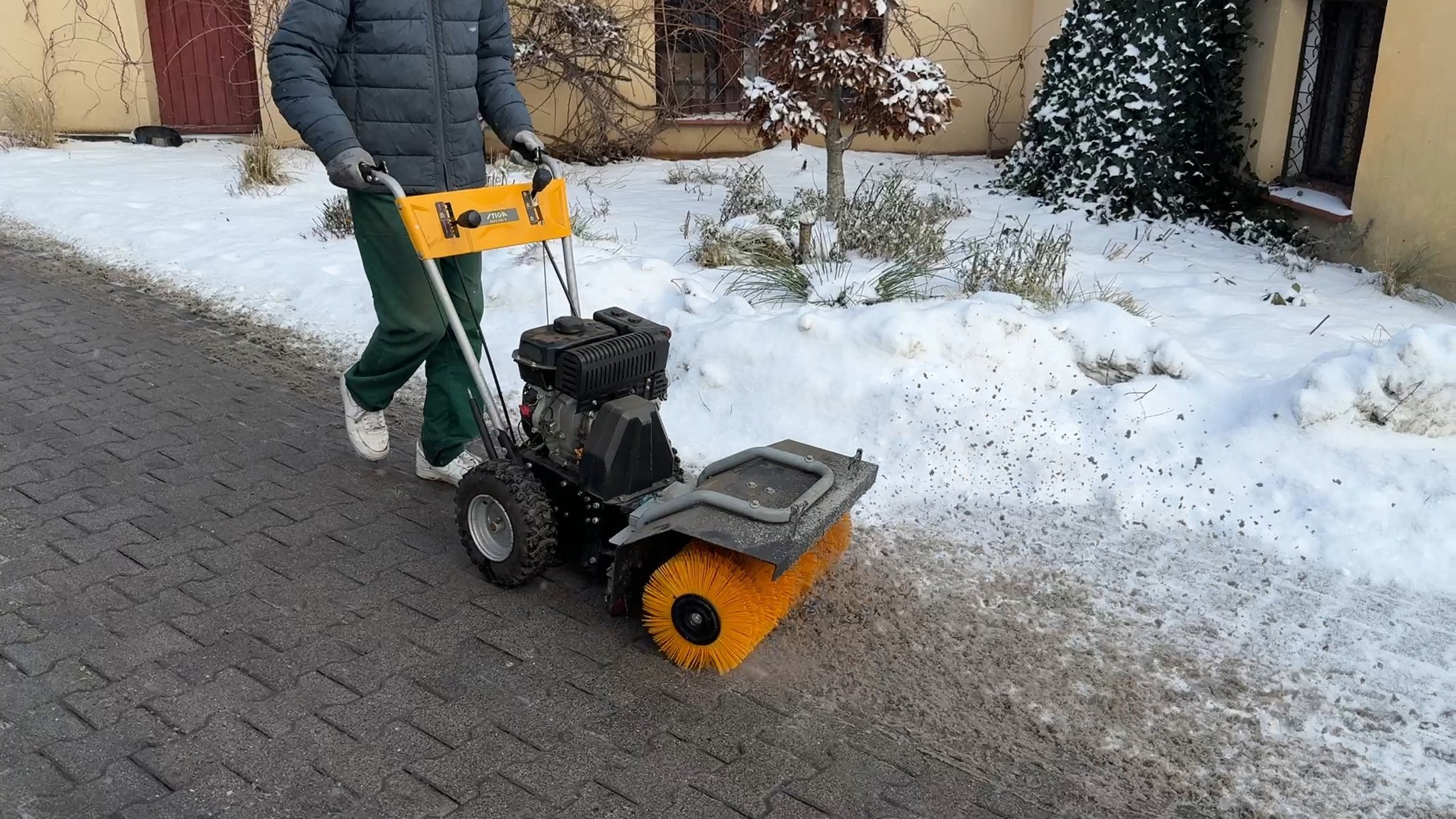 Zamiatarka mechaniczna usuwa śnieg z chodnika z kostki brukowej — zimowe utrzymanie nawierzchni